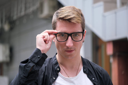 Portrait of a young handsome guy in a black shirt with glasses close-up autumn street photography