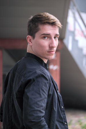Portrait of a young handsome guy in a black shirt close-up autumn street photographyの写真素材