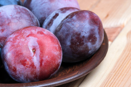 Sweet ripe unwashed plums with natural wax on the peel on a light wooden table close-upの写真素材