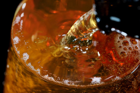 Fresh live light beer is poured into a glass goblet on a black background macro photographyの写真素材