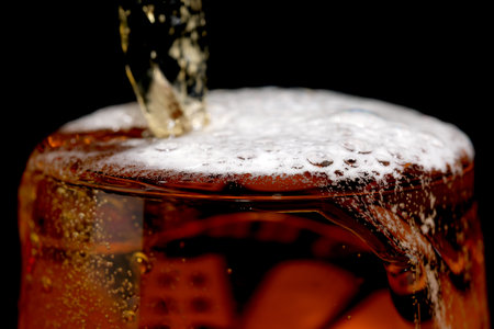 Fresh live light beer is poured into a glass goblet on a black background macro photographyの写真素材