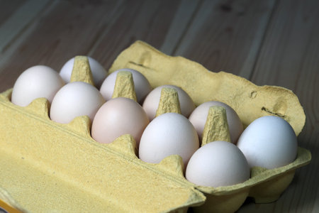 Raw chicken eggs in a tray on a wooden table close-up macro photography