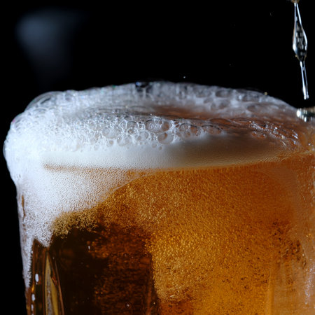 Fresh cold light barley beer is poured into a glass glass on a black background close-upの写真素材