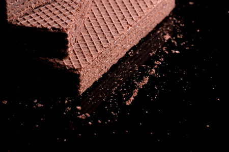 Delicious fresh waffles with hazelnut chocolate cream close-up on black mirror backgroundの写真素材
