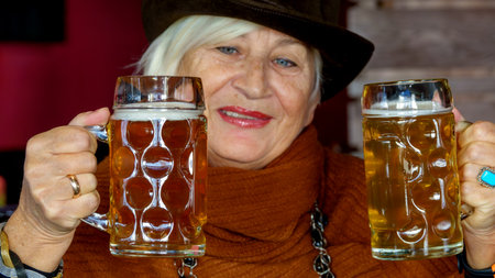 Elderly gray-haired pretty cheerful optimistic woman is resting in a beer barの写真素材