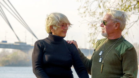Portrait of an elderly gray-haired couple, a man in militarized khaki clothes, a woman in a black...