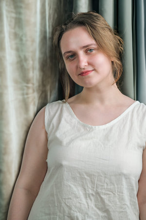 Portrait of a young attractive girl in a white shirt on a light background close-up