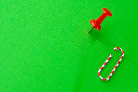 Red paperclip and red button on green blank sheets, stationery art background, macroの写真素材