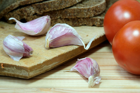 A cutting board topped with sliced tomatoes and garlic.の写真素材