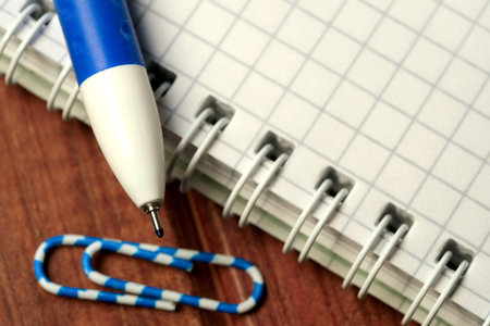 A blue pen rests beside a grid notebook and a paperclip suggesting inspiration.