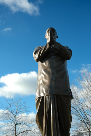 A bronze statue stands under a clear blue sky.の写真素材