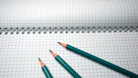 Writing tools sit poised on a grid notebook, inviting inspiration.の写真素材