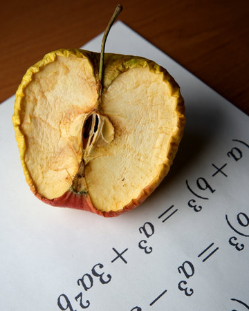 A half apple rests on a table, showing its texture among math equations.の写真素材