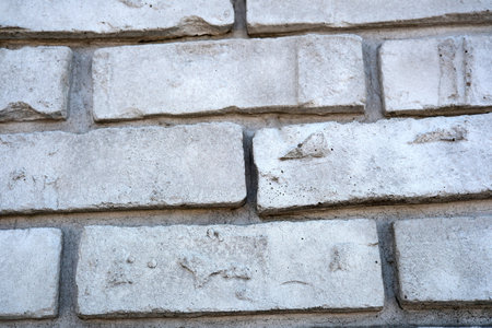 Close-up view of a weathered brick wall exhibiting unique textures and colors.の写真素材