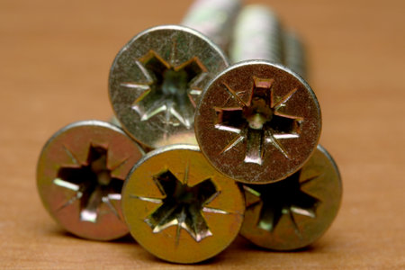 Shiny screws rest on a warm wooden surface, showing their details.の写真素材