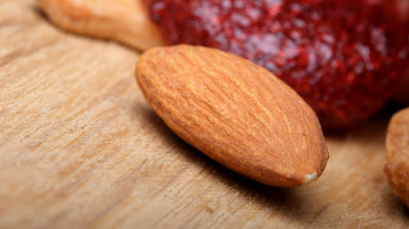 Creamy almond spread sits next to nuts on a textured wooden surface.の写真素材