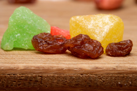Bright candy and dried fruit pieces lay artfully on a wooden surface.の写真素材