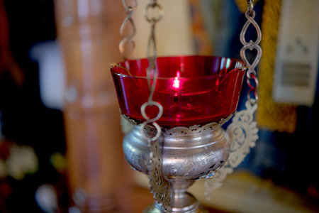 Intricate silver lamp with a glowing red bowl enhances the ambiance of devotion.の写真素材