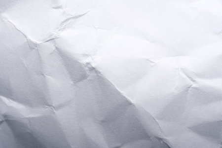 A crumpled white surface casts shadows, highlighting its texture.の写真素材
