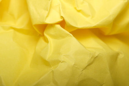 A crumpled yellow surface captures light and adds cheerful energy.の写真素材