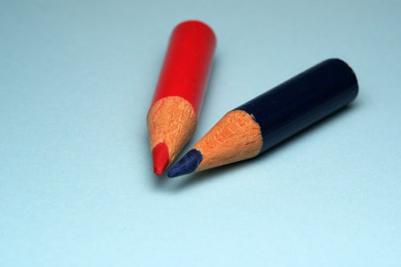 Red and blue coloring pencils rest side by side on a light surface.の写真素材