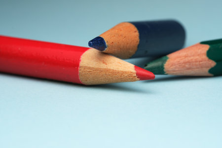 Three colorful pencils rest on a smooth surface, ready for artistic creation.の写真素材