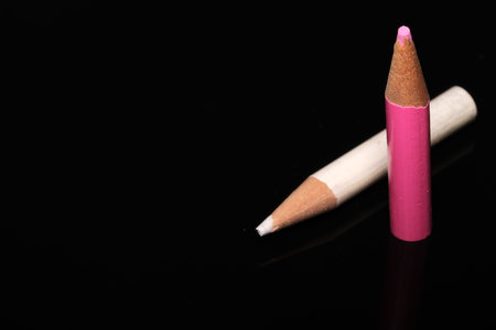Two vibrant pencils rest on a sleek black surface, showing artistic potential.