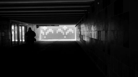 A mysterious silhouette ventures through a dim corridor into bright surroundings.の写真素材