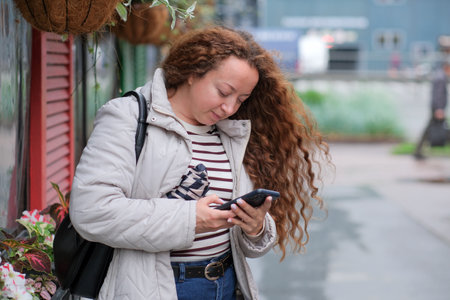 Young woman enjoys a moment of connection on a rainy city sidewalk.の写真素材