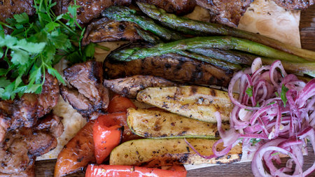 A tantalizing array of grilled meats and fresh vegetables garnished with herbs.の写真素材