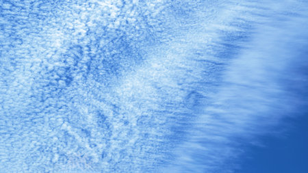 Soft clouds gracefully drift across a bright blue sky, creating a calming atmosphere.