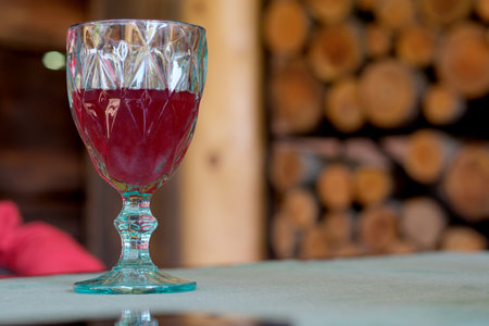 A vibrant glass of berry drink rests on a table amidst a cozy wooden ambiance.の写真素材