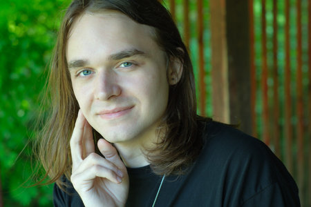 A young man with long hair enjoys a peaceful moment surrounded by nature.