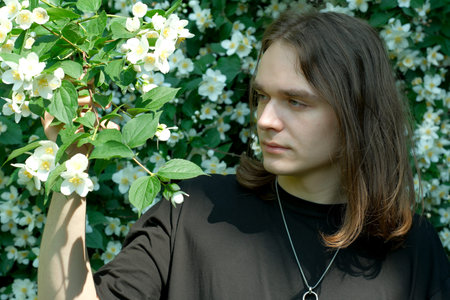 A young man admires flowers in a vibrant garden full of color.