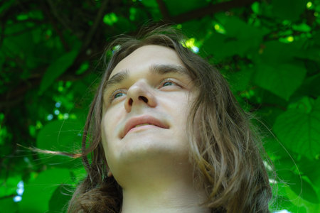 A young person gazes upward, immersed in tranquility beneath vibrant leaves.