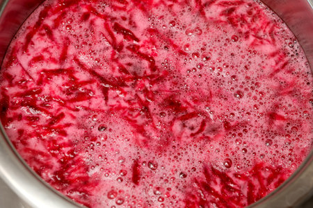 Vibrant beetroot juice bubbles in a silver pot, ready for a lively feast.の写真素材