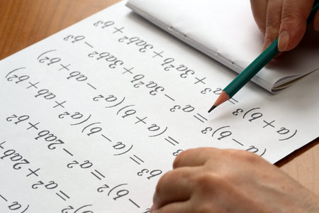 A person focuses on solving math problems with a green pencil, surrounded by notes.