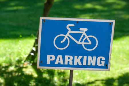 A vibrant blue sign indicates designated parking for bicycles amidst green grass.の写真素材