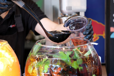 Hands skillfully pour a rich drink blend into a cup, surrounded by fresh ingredients.の写真素材