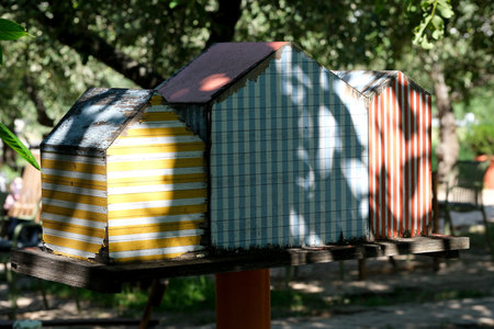 Brightly painted wooden houses stand under the trees, casting playful shadows.の写真素材