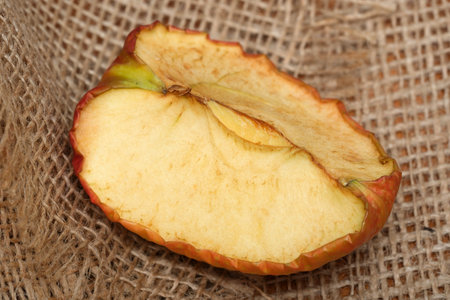 A fresh apple slice rests on textured burlap, showing its vibrant colors.