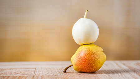 A pear supports a round white fruit, showcasing a playful display of shapes.の素材