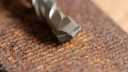 Rusty wood grain highlights the intricacies of the drill bit resting nearby.の写真素材