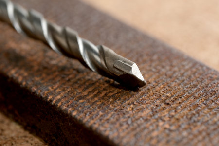 A rusty drill bit on textured wood highlights the essence of craftsmanship.
