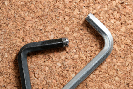 Two different types of hex keys lie on a cork surface, ready for use in construction.