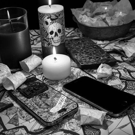 Candles flicker softly illuminating a table filled with unique objects and shadows.の素材