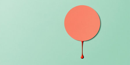 A bold circular shape drips color onto a soft green surface, creating a striking visual.の素材
