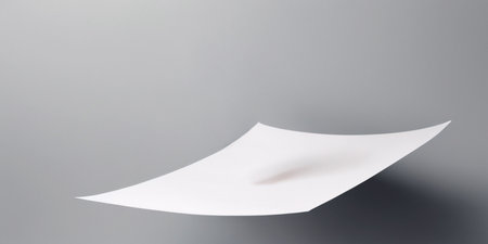 A delicate sheet of paper appears to hover above a smooth surface, softly lit from above.の素材