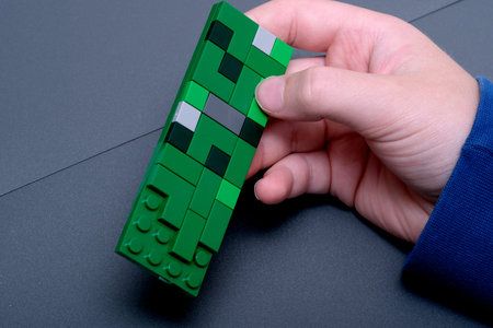 A child constructs a green block design at a table, focusing intently on details.