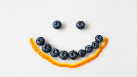 Fresh blueberries and orange slices arranged in a delightful smile pattern on a surface.の素材